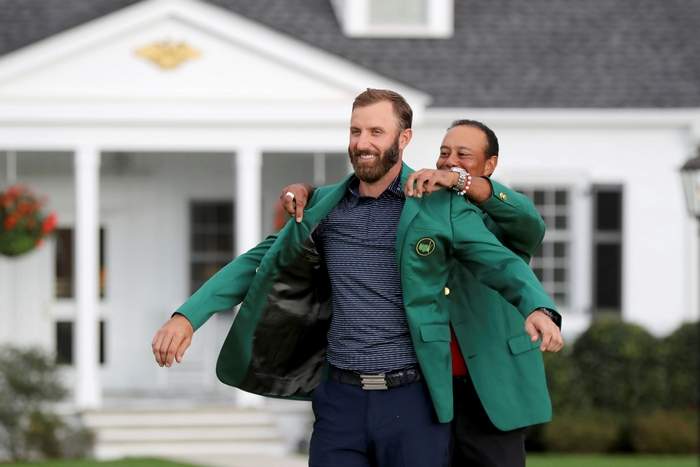 Dustin Johnson (left) receives his Green Jacket from former 5-time Masters Champion Tiger Woods (right).