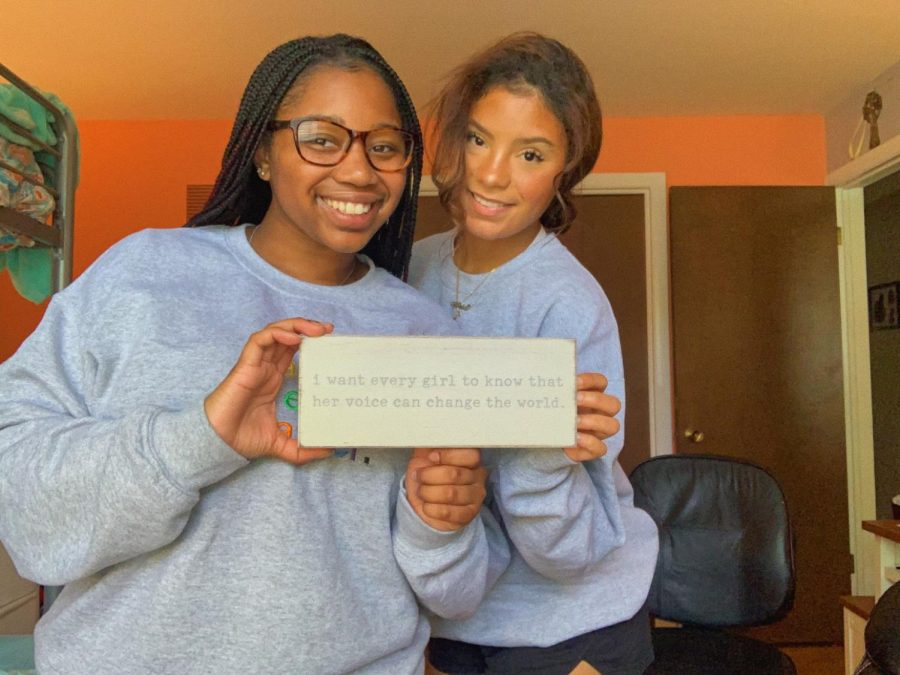 Sline (right) and Nottke (left) pose with a sign that reads, I want every girl to know that her voice can change the world. The pair is also wearing their (f)embolden embroidered crewnecks. 