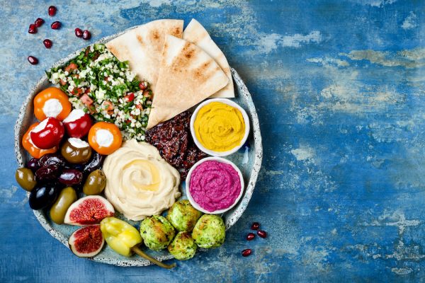 Middle Eastern meze platter with green falafel, pita, sun dried tomatoes, pumpkin and beet hummus, olives, stuffed peppers, tabbouleh, figs. Mediterranean appetizer party idea (Middle Eastern meze platter with green falafel, pita, sun dried tomatoes,